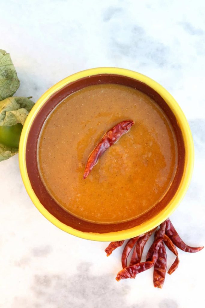 Roasted Tomatillo Salsa with a Chile de arbol and surrounded by more chiles and tomatillos
