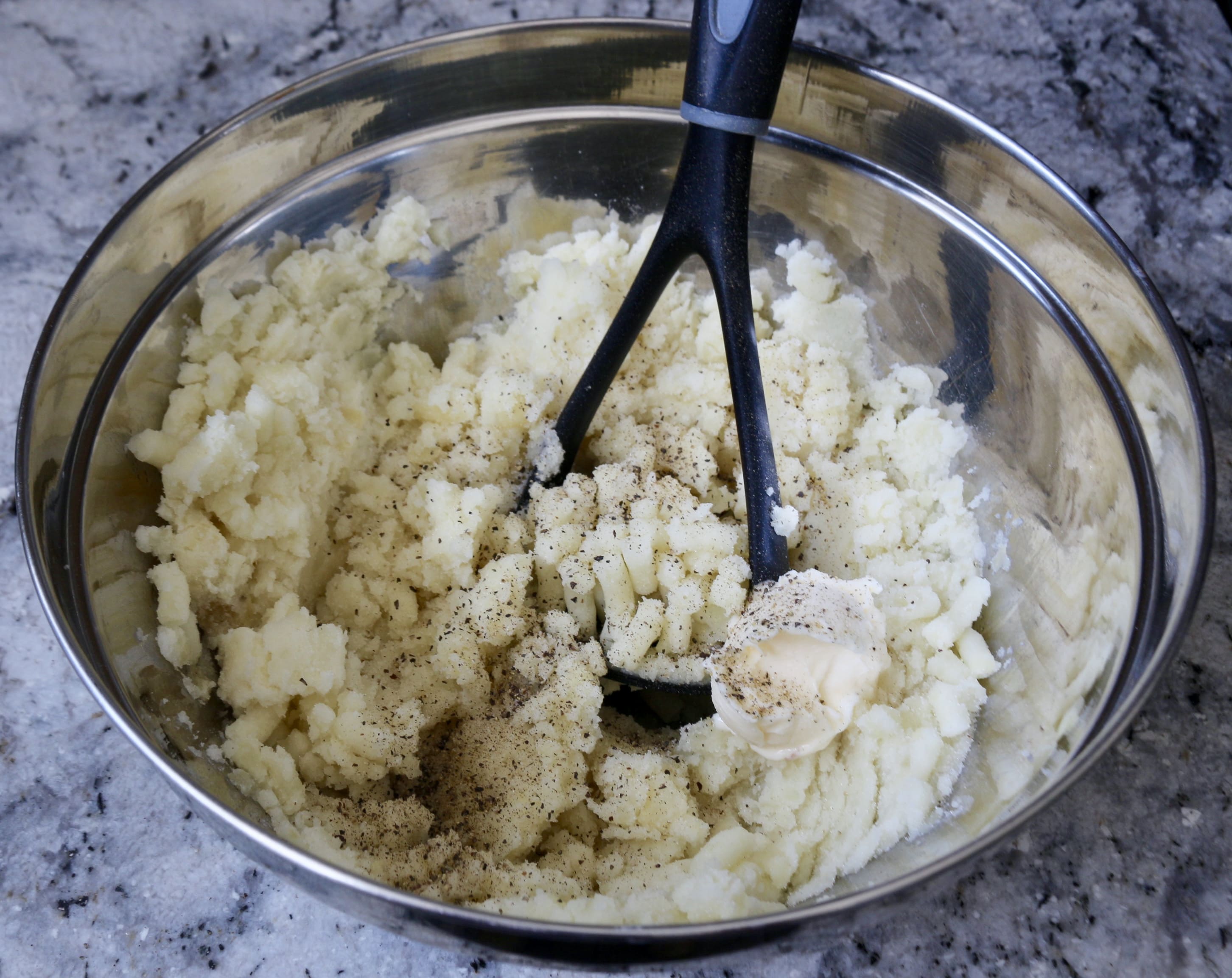 Mashing potatoes for potato patties with chile con queso