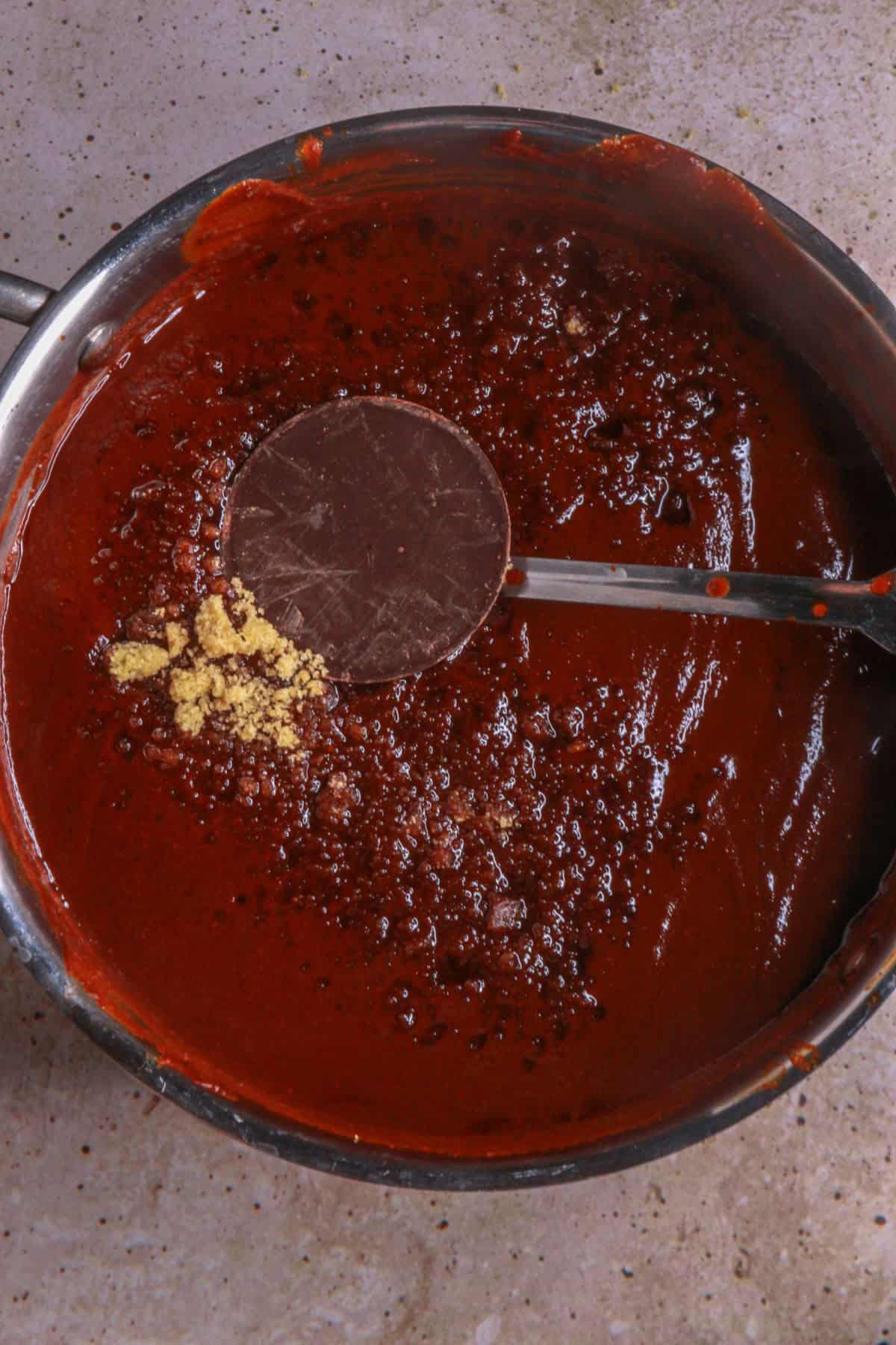 Adding chocolate and sugar to mole sauce