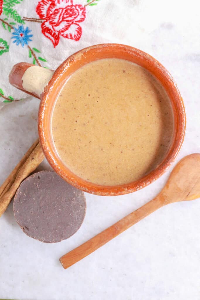 Overhead view of a cup of creamy Mexican champurrado with cinnamon and Mexican chocolate.