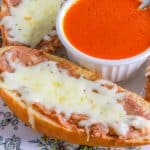 Cheesy molletes Mexicanos on a plate with a bowl of chipotle sauce in the middle