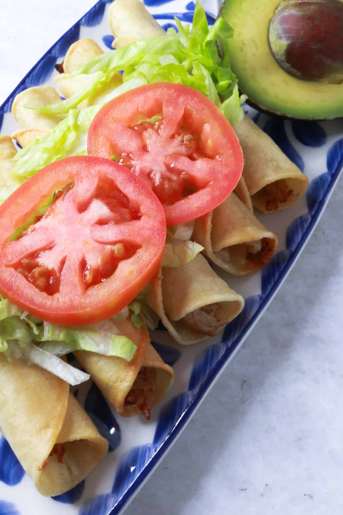 Pork Flautas topped with lettuce and tomato