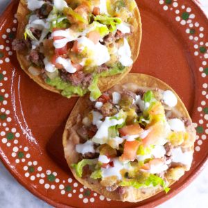 Ground Beef Tostadas with Refried Beans on a brown Mexican plate