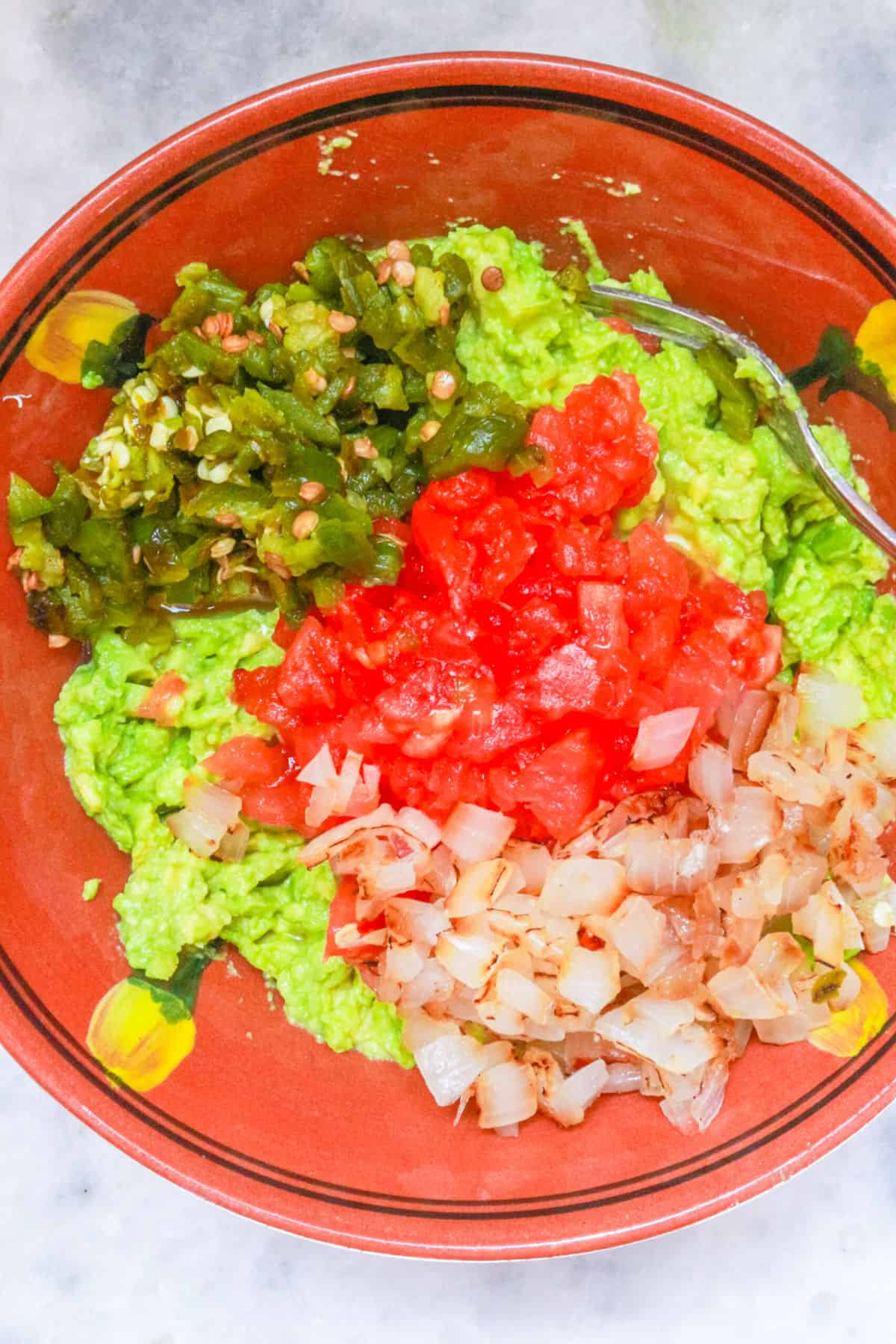 Chopped roasted vegetables in a bowl with mashed avocados