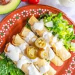 Plate with flautas de pollo drizzled with jalapeño sour cream