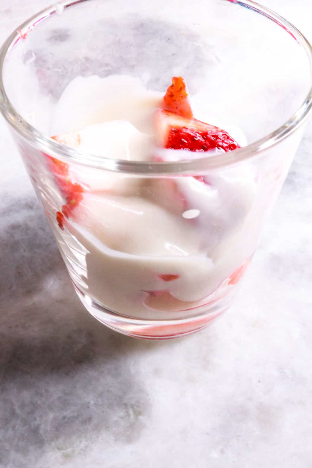 glass jar being filled with layers of fresas con crema
