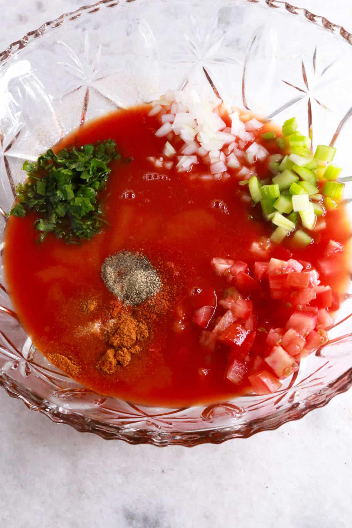 Glass mixing bowl with tomato sauce, spices and diced vegetables for coctel de Cameron