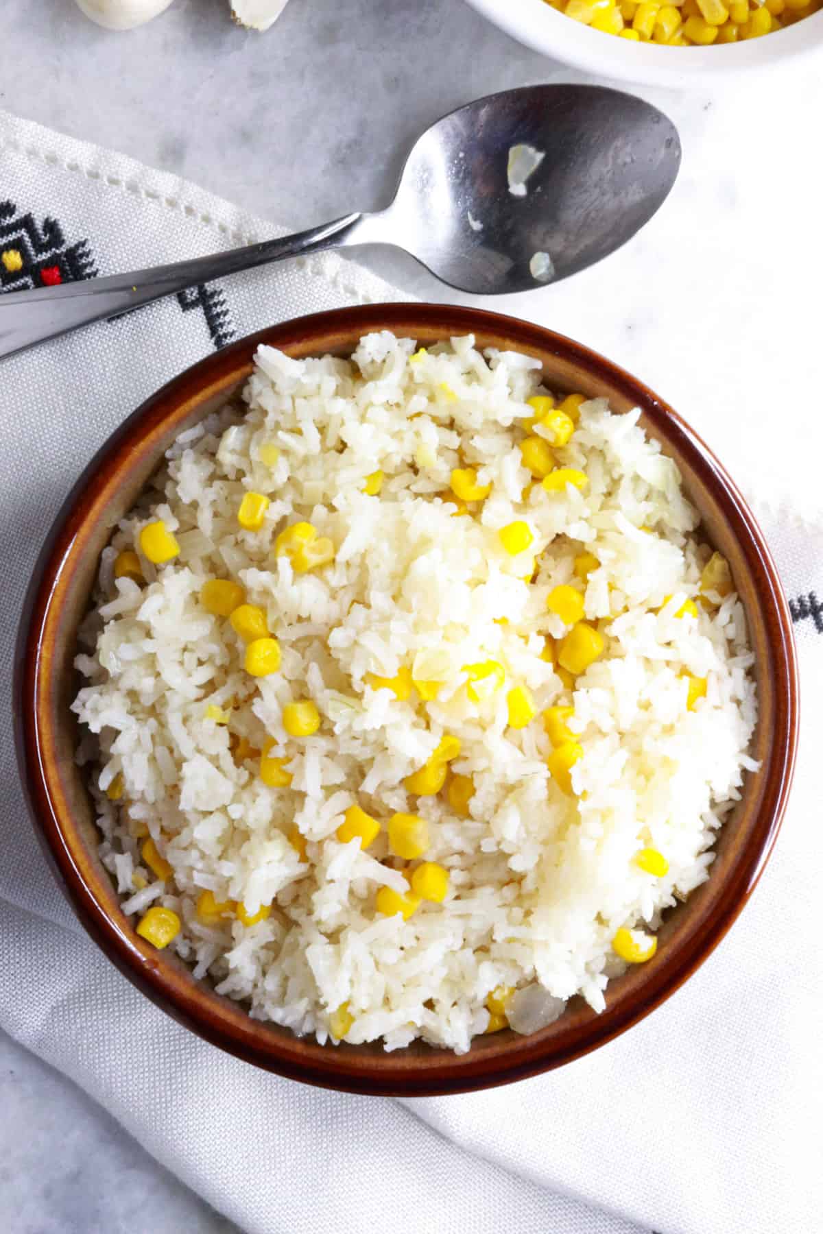 Top view of a bowl with white rice with corn on a white background