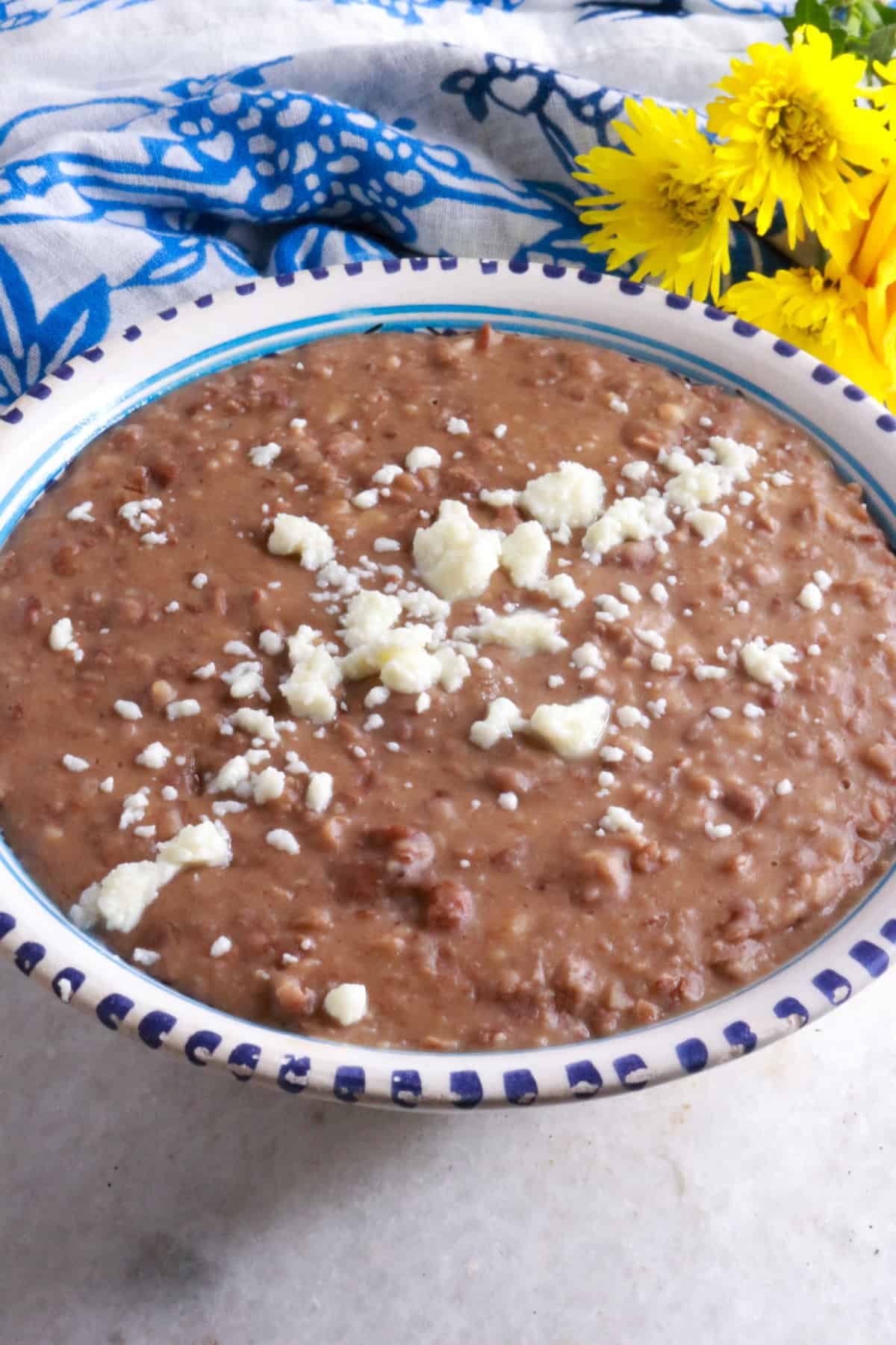 A bowl with creamy refried beans with a some crumbled queso fresco on top