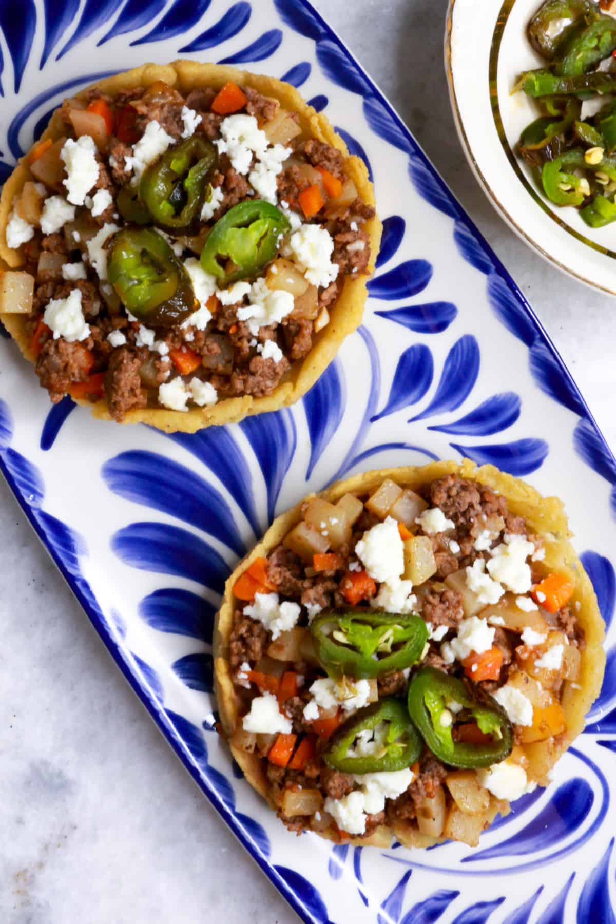 Two Mexican Picadillo sopes on a blue and white Mexican platter