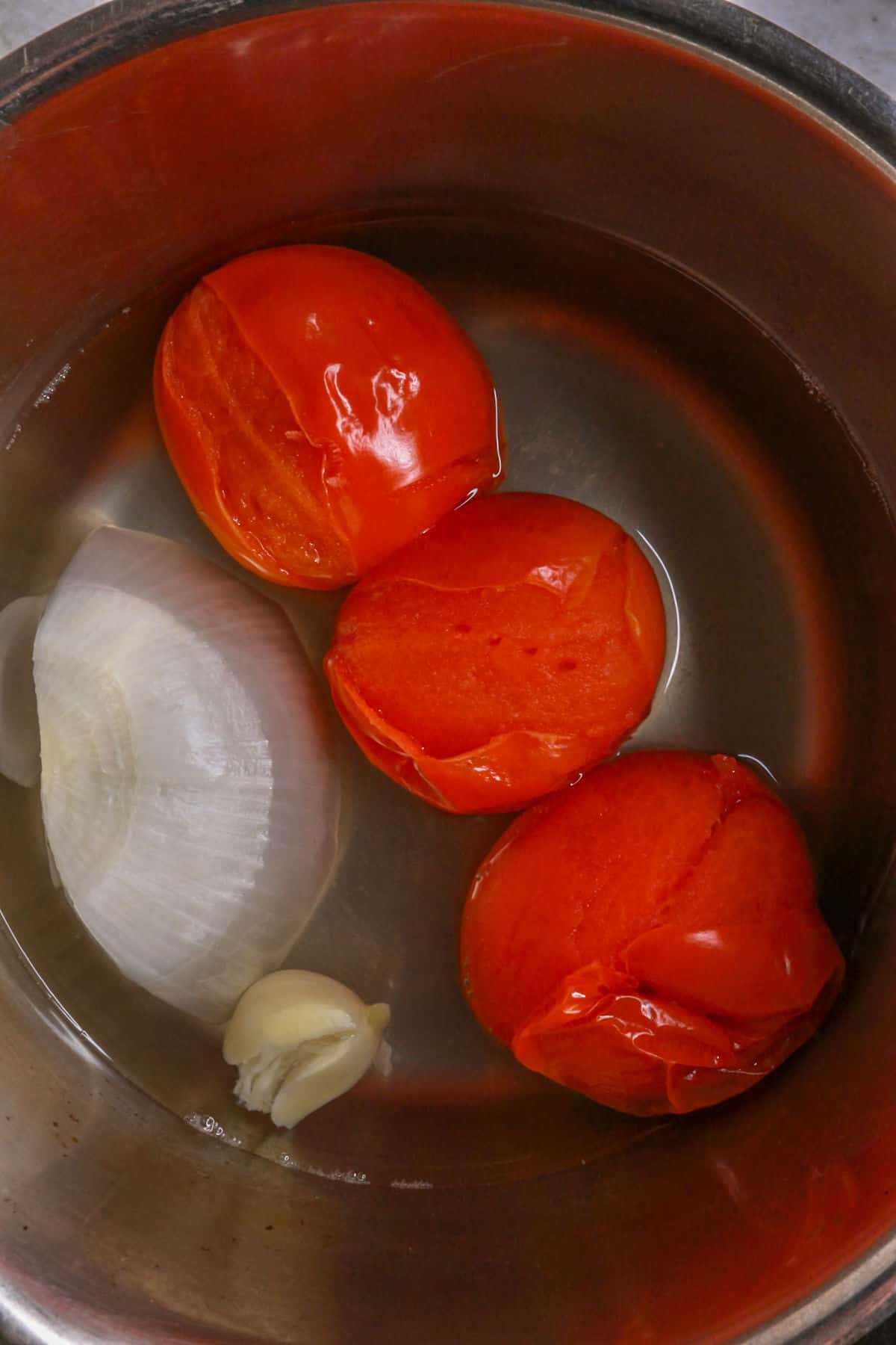 3 tomatoes, a piece of onion, garlic and water in a small pot