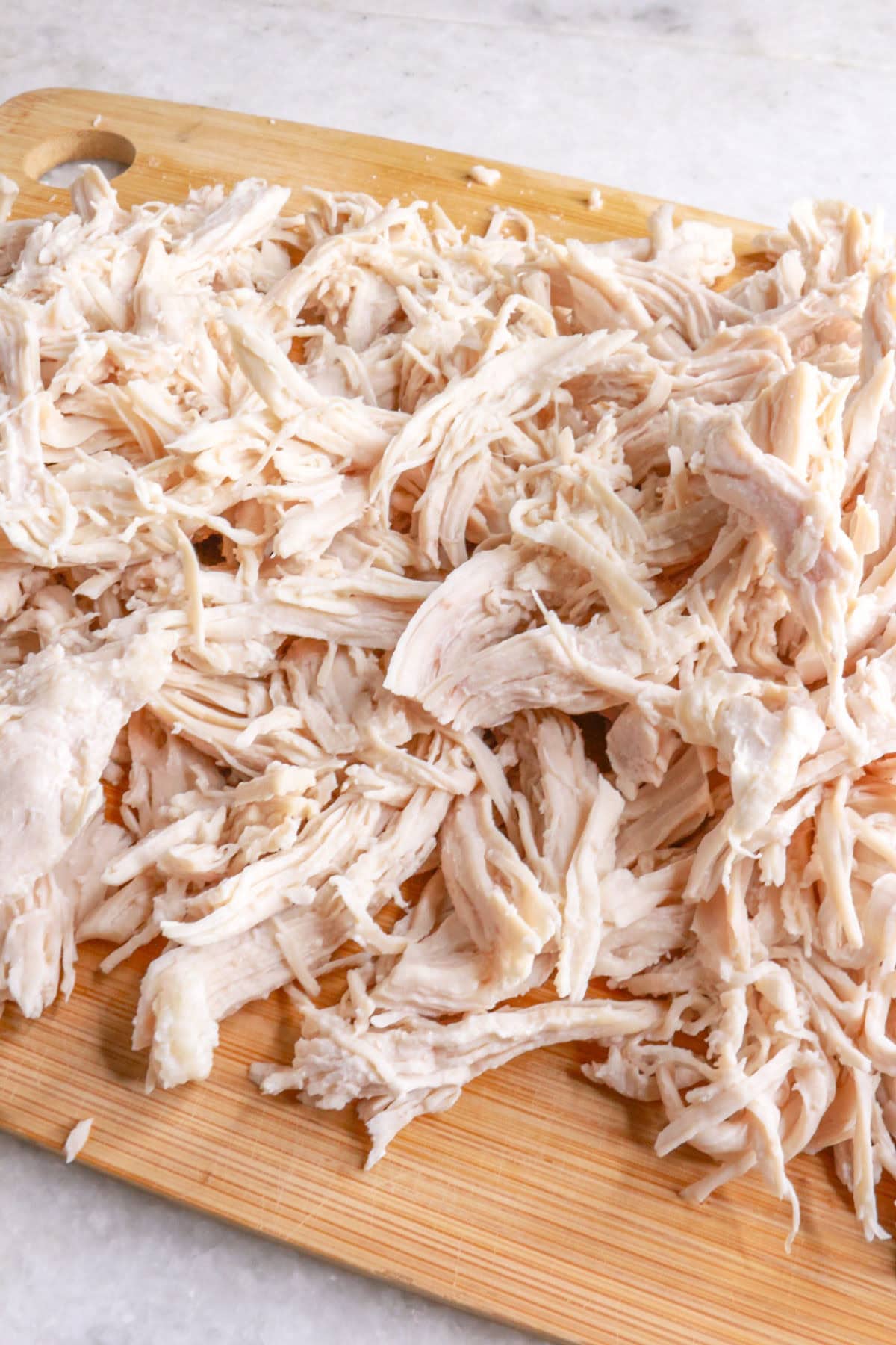 Shredded chicken on a wooden cutting board
