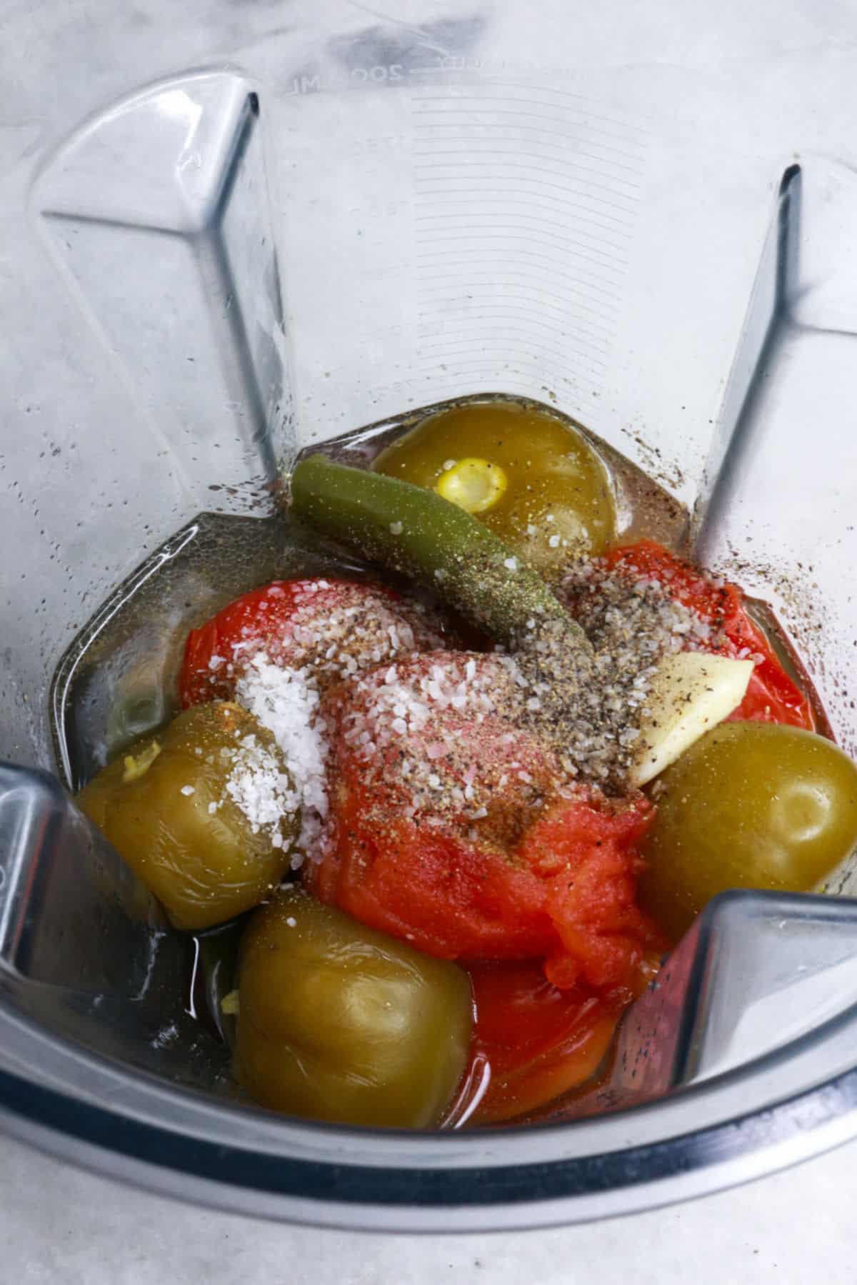 Tomatillos, tomatoes, jalapeños and spices in a blender