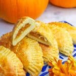 Cut empanada de calabaza on top of other pumpkin empanadas on a platter