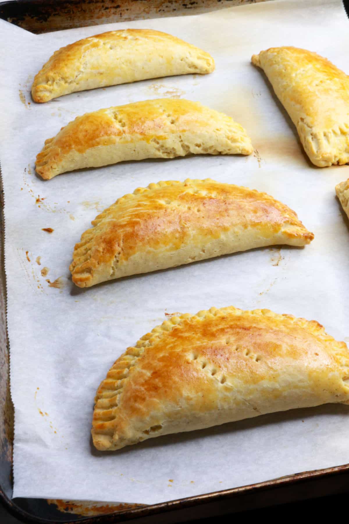 Baked empanadas on a baking sheet with parchment paper