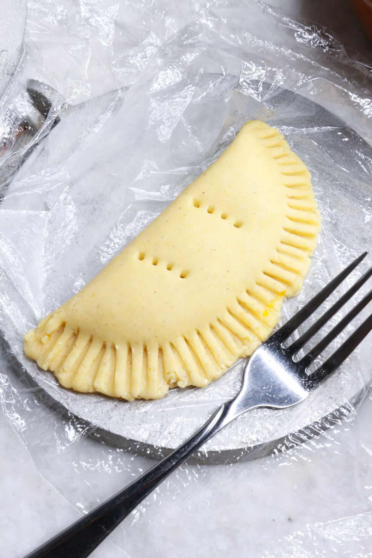 Raw empanada with the edges sealed with a fork