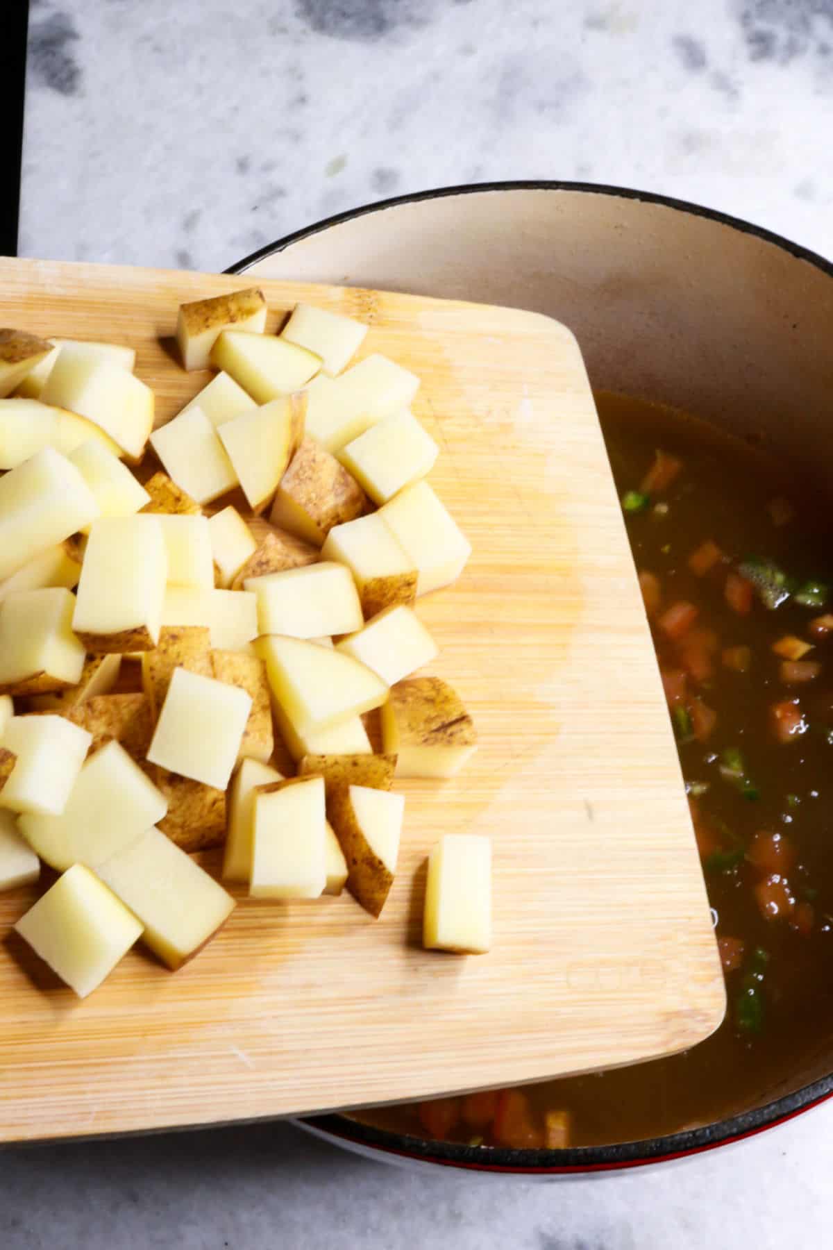 Adding potatoes to a pot of stew