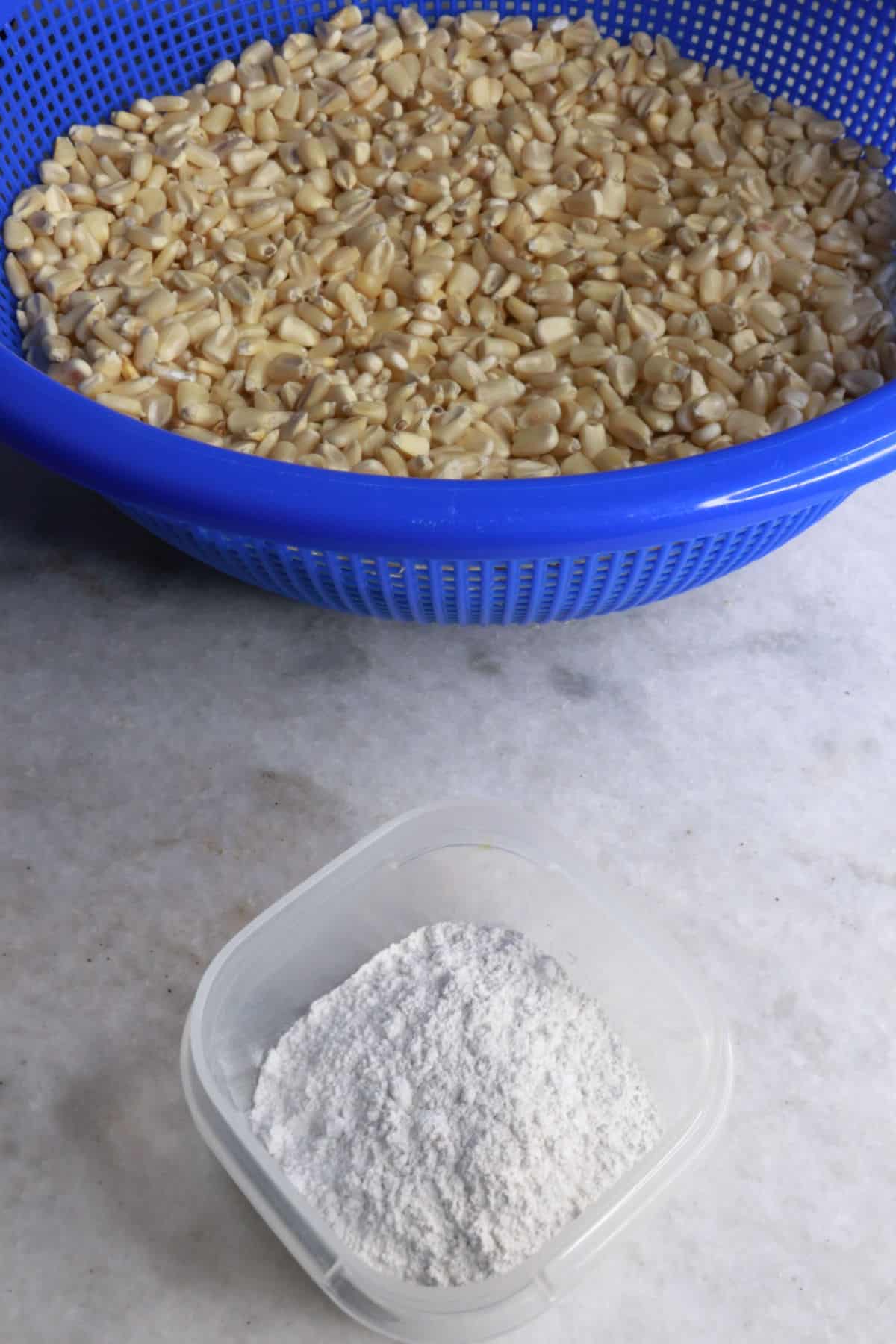 A big bowl with dried white corn and a small container with calcium hydroxide