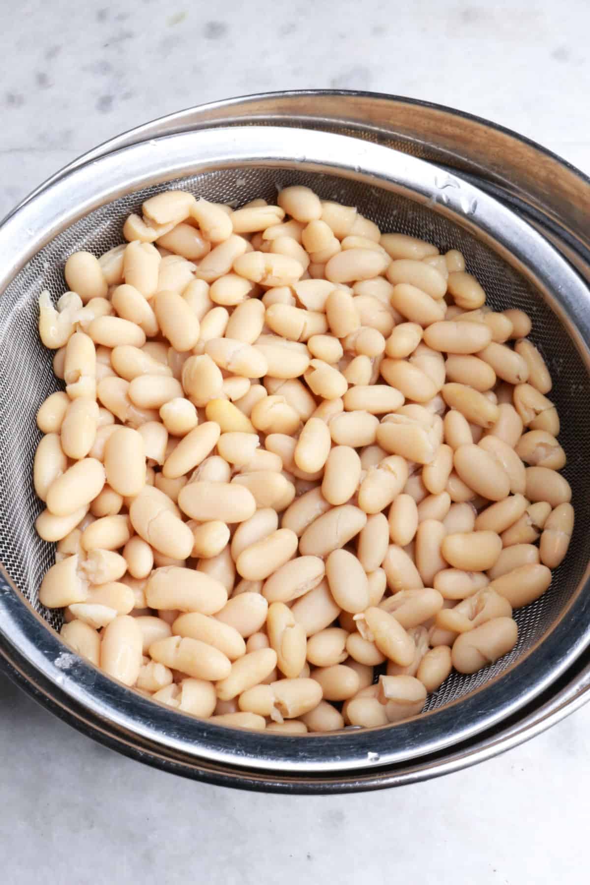 White beans in a colander over a bowl