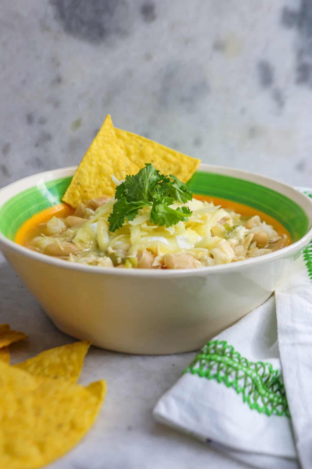 Bowl of white chicken chili with hominy with garnishes and tortillas chips