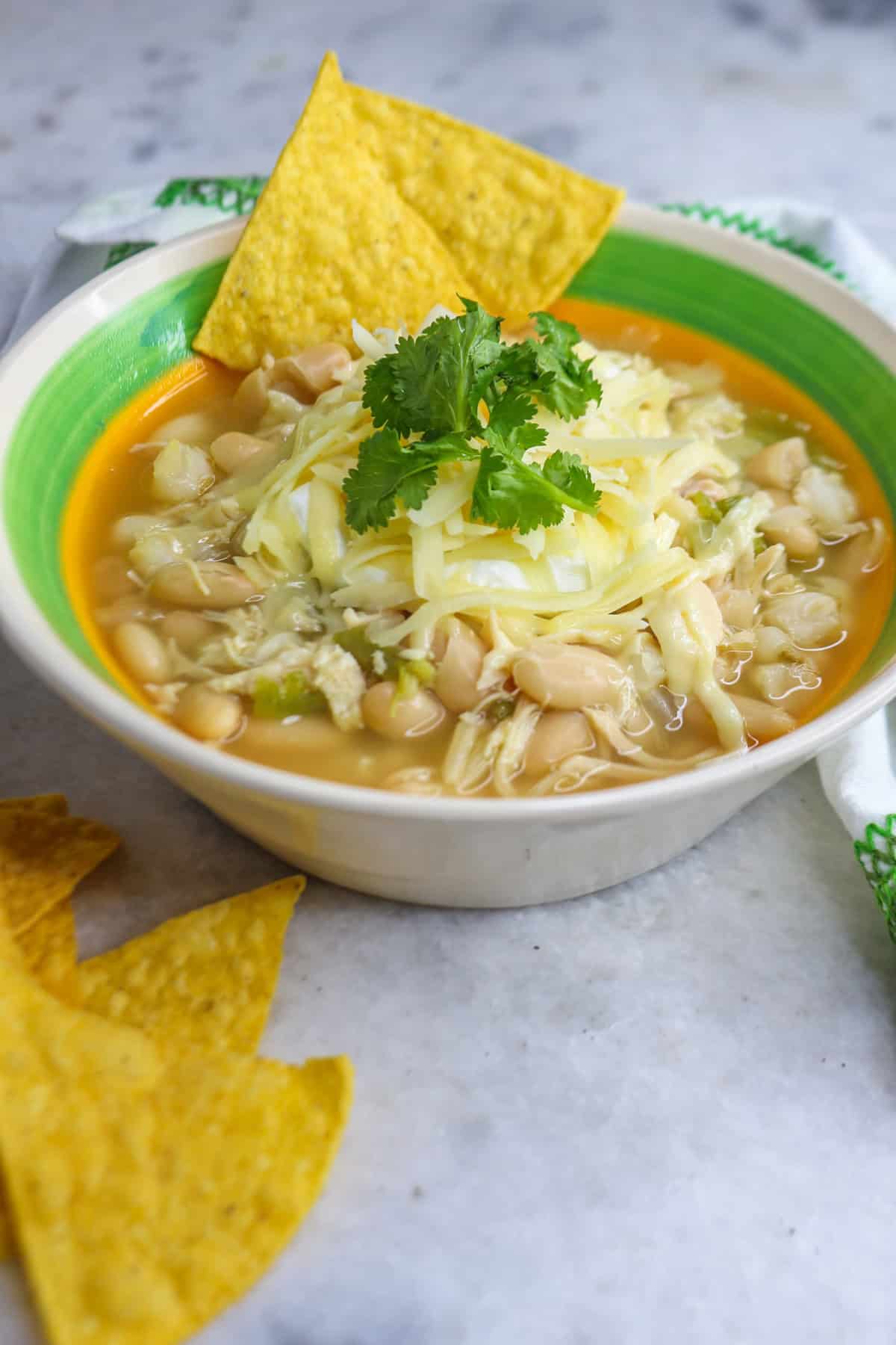 Bowl of white chicken chili with hominy with garnishes and tortillas chips