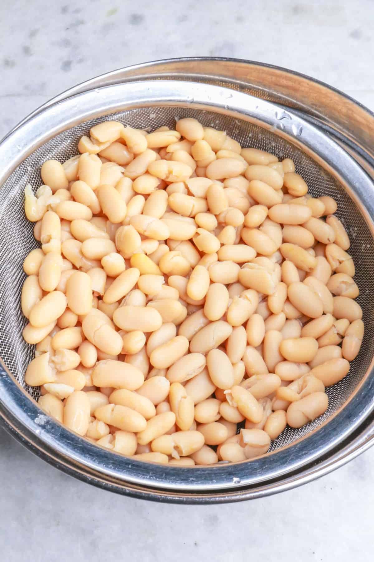 Draining white beans on a mesh sieve
