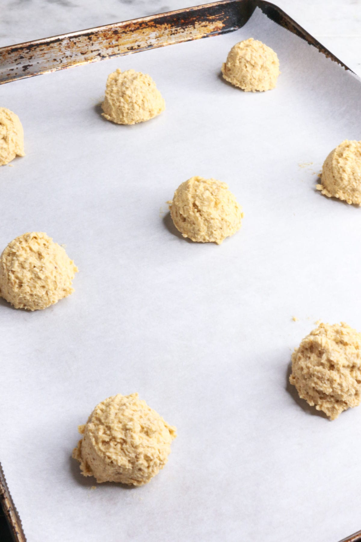 Spoonfuls of raw coconut cookies on a cookie sheet