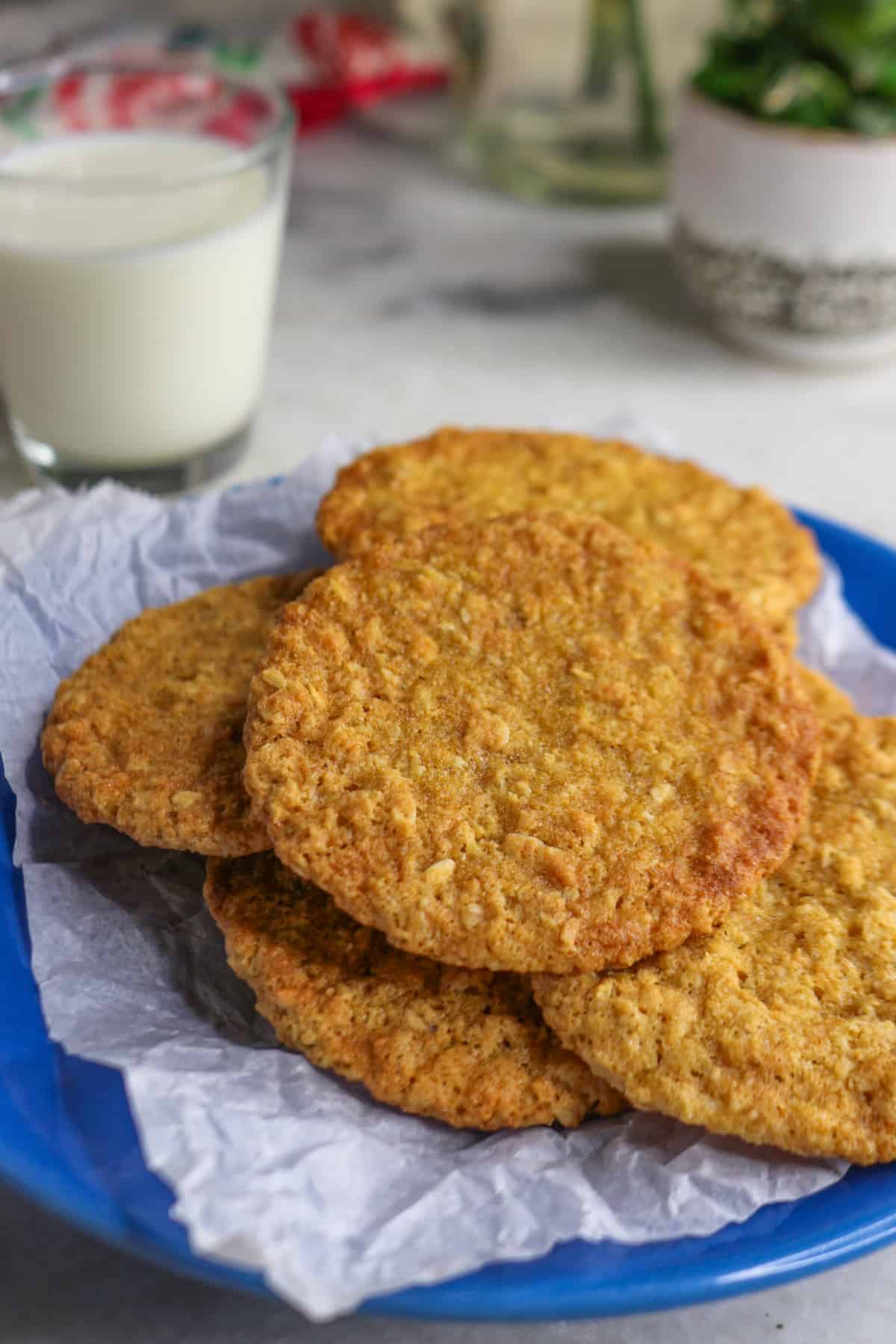 Coconut flour oatmeal cookies on a blue plate with a glass of milk behind it.
