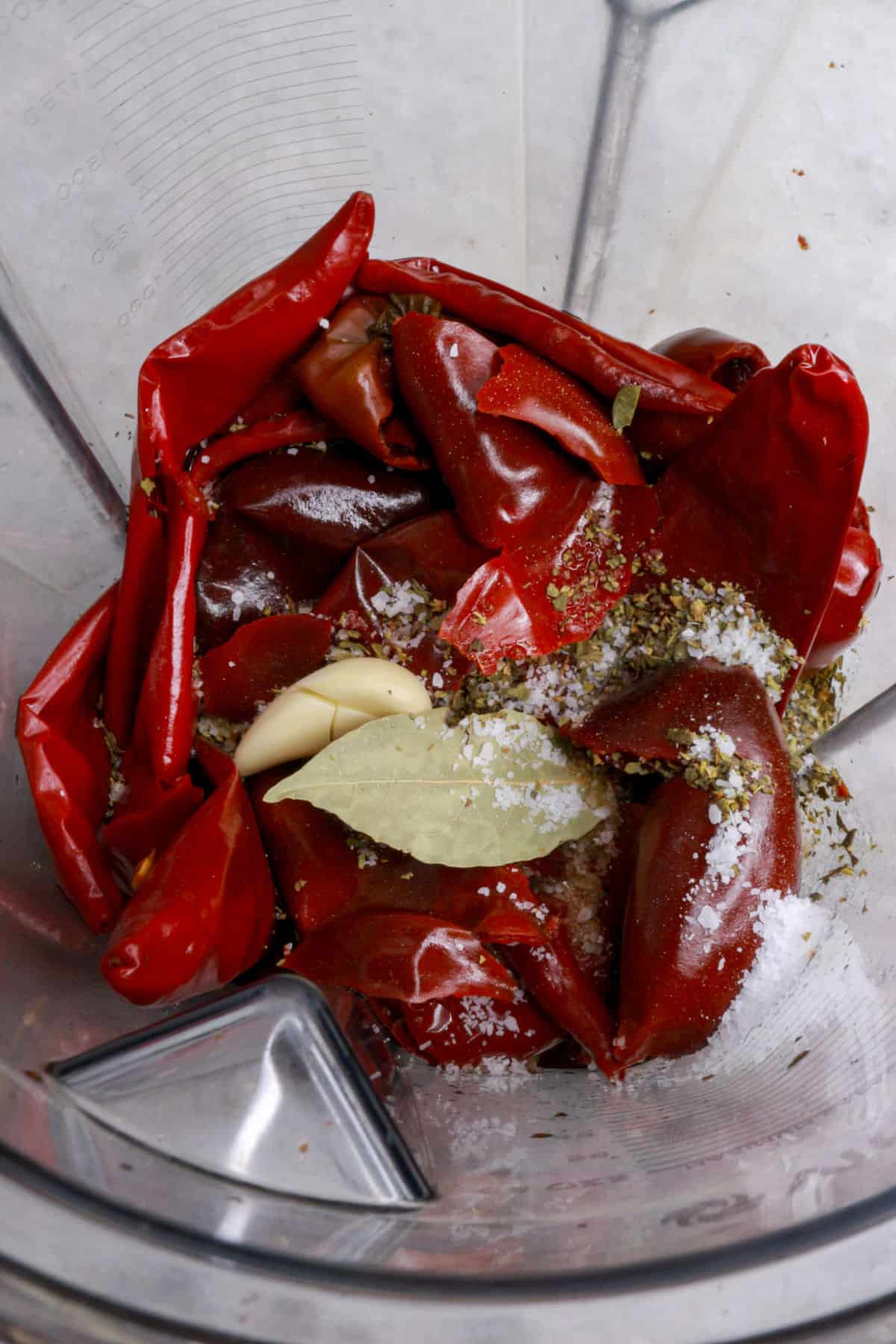 A blender with boiled red chiles, spices and dried herbs