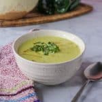 Poblano cream soup in a bowl garnished with tortilla strips and cilantro