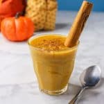 Pumpkin arroz con leche in a glass cup garnished with a cinnamon stick