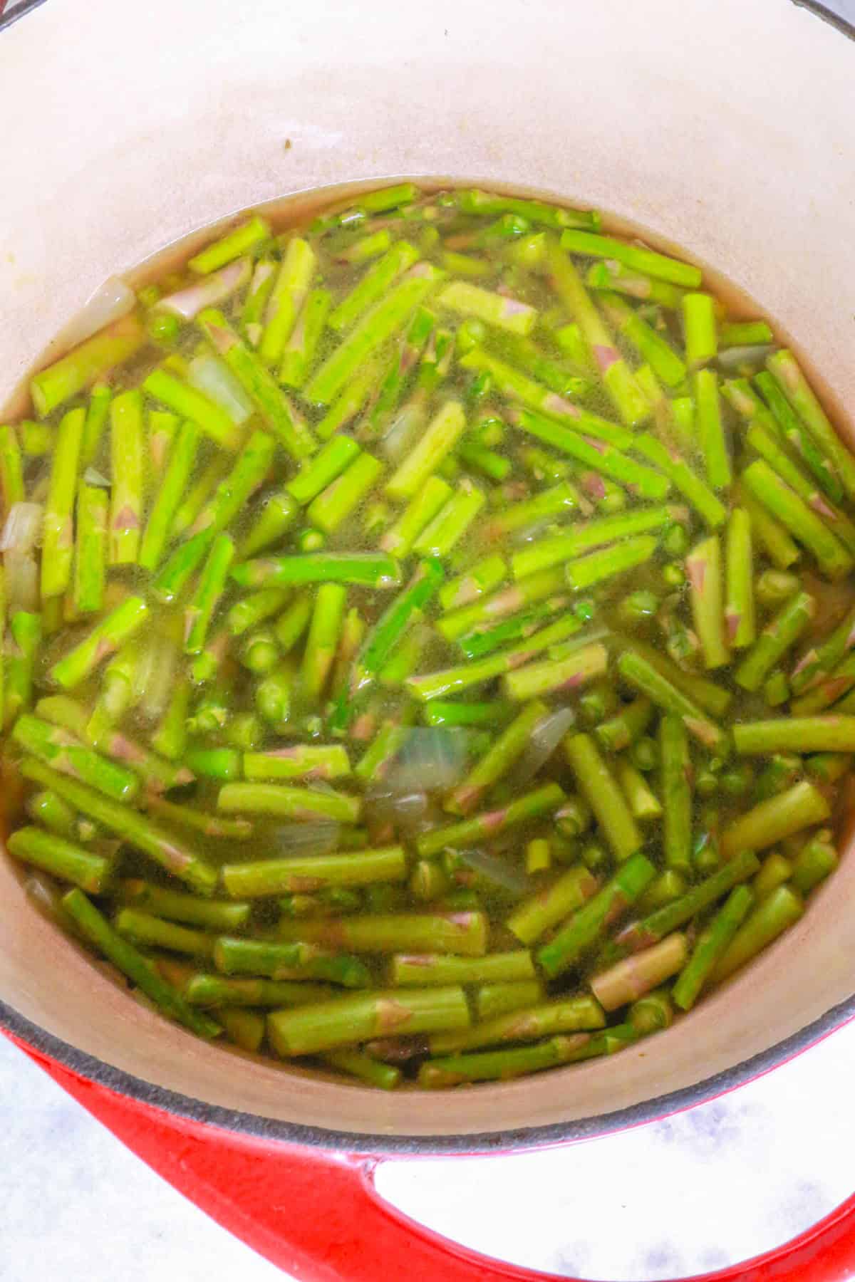 Pot with simmering asparagus pieces in broth