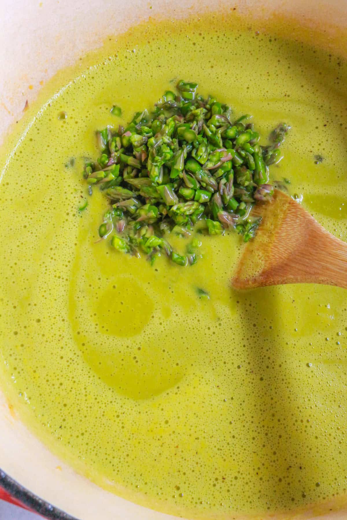 Adding diced asparagus to a pot of cream of asparagus soup