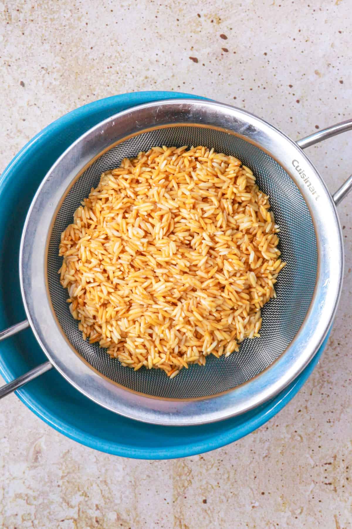 Toasted rice on a sieve over a bowl to drain the excess oil