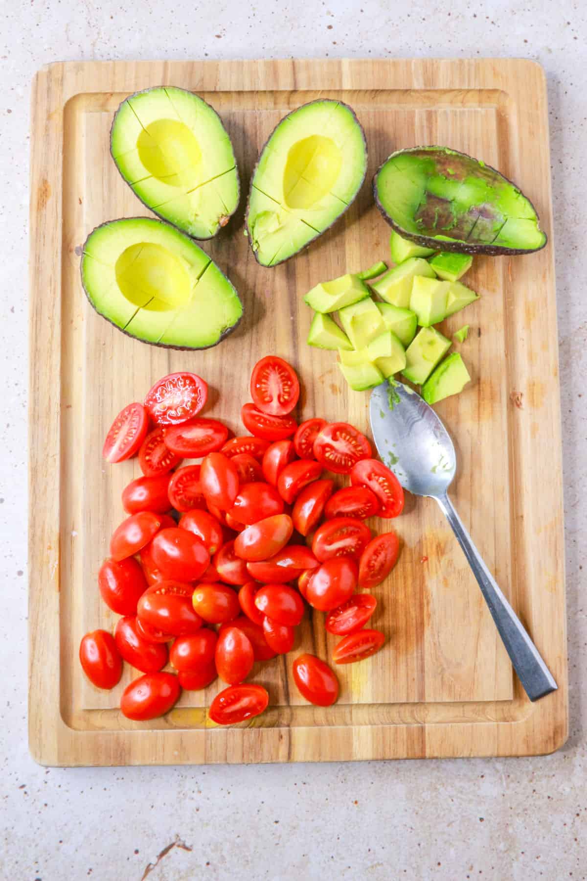 diced avocados and halved cherry tomatoes on a cutting board