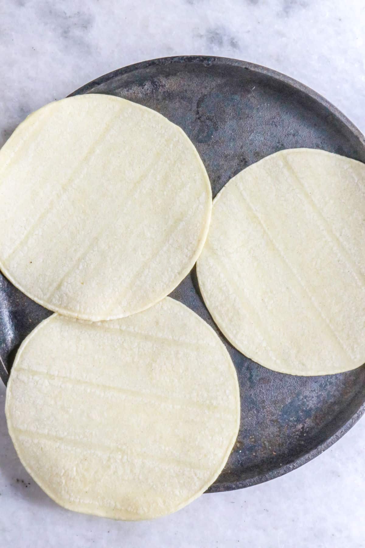 Corn tortillas being warmed on a coal