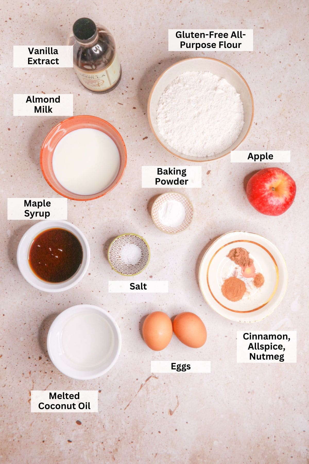 Ingredients for muffins de manzana y avena: vanilla, gluten-free oat flour, baking powder, apple, maple syrup, salt, spices, egg, almond milk, coconut oil