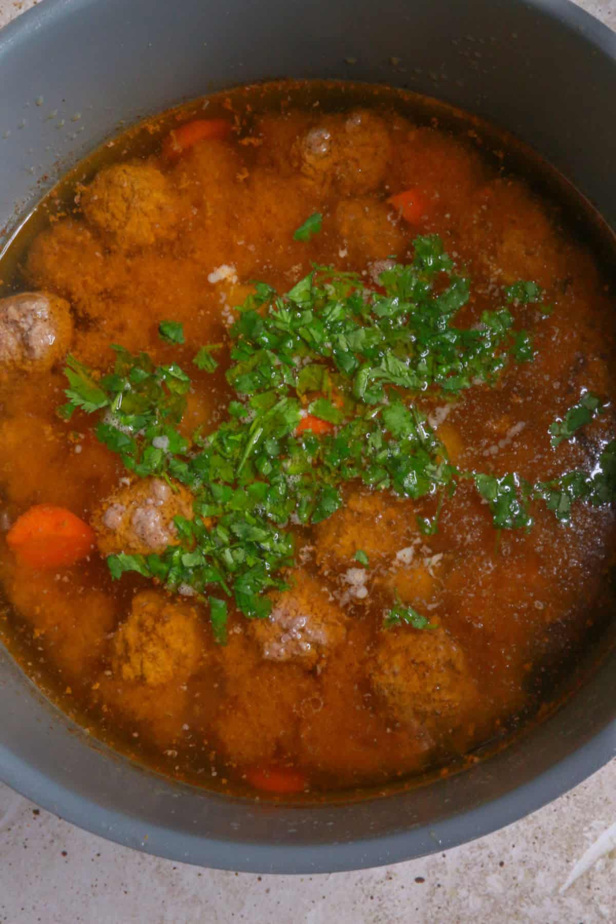 Meatball soup with chopped cilantro simmering