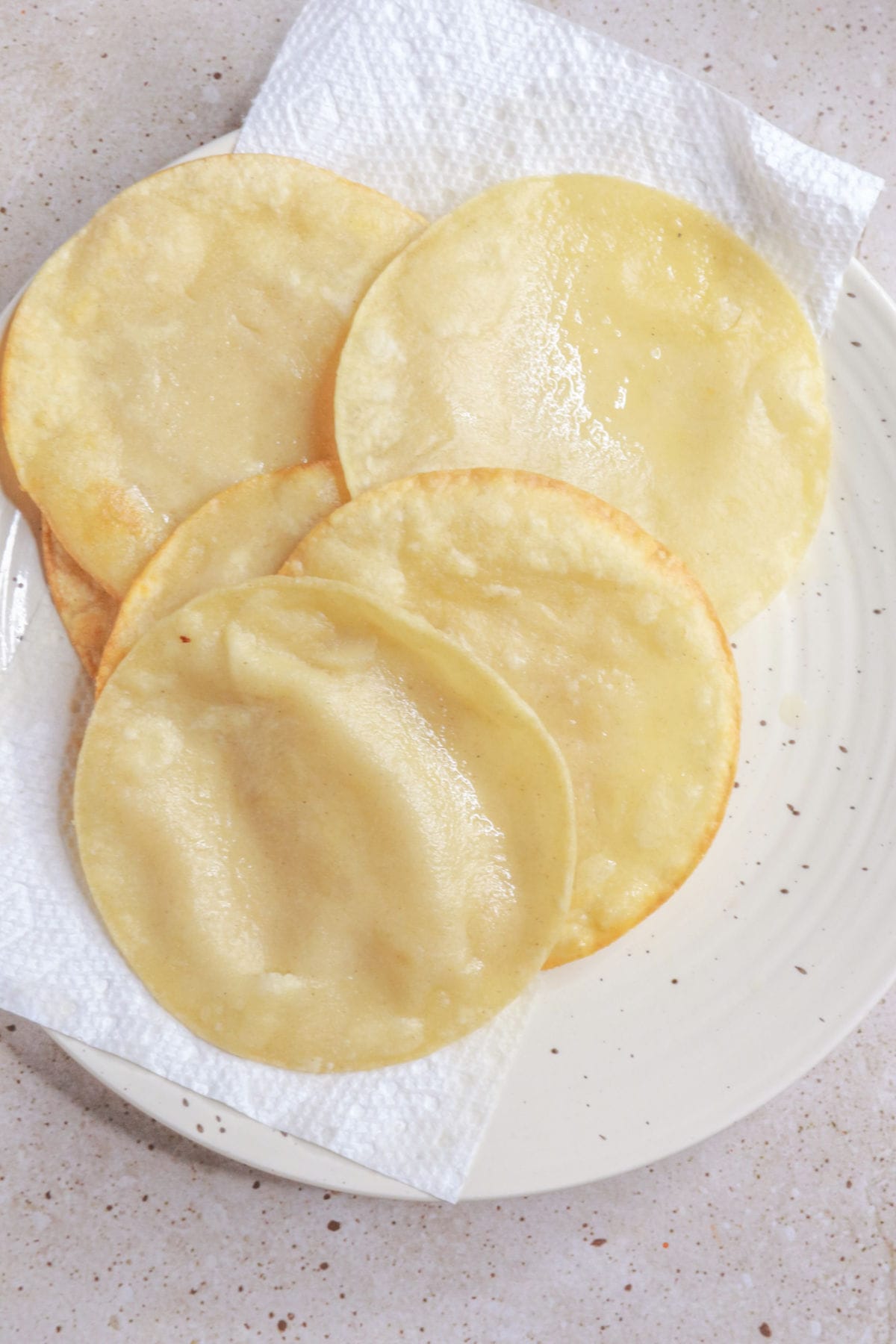 Drain fried tortillas on a paper towel-lined plate