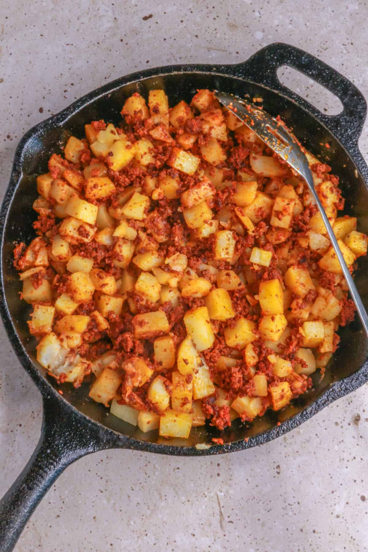 Mixing papas con chorizo in skillet