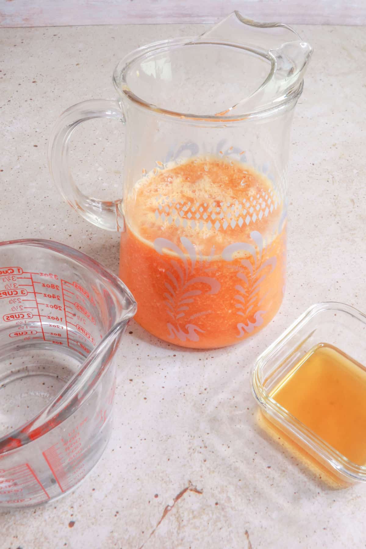 Pitcher with agua fresca, container with honey simple syrup and measuring cup with water