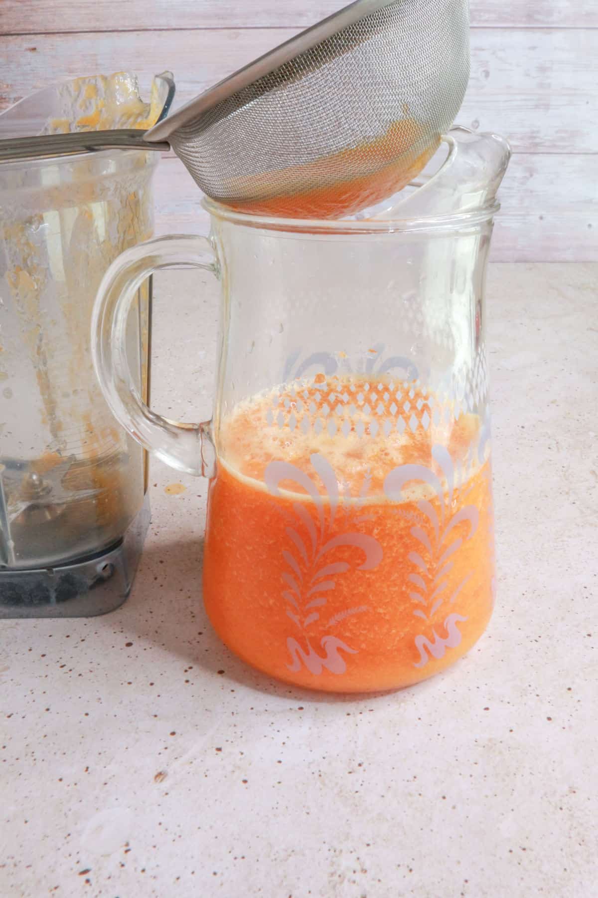 Straining agua de papaya with sieve into a pitcher