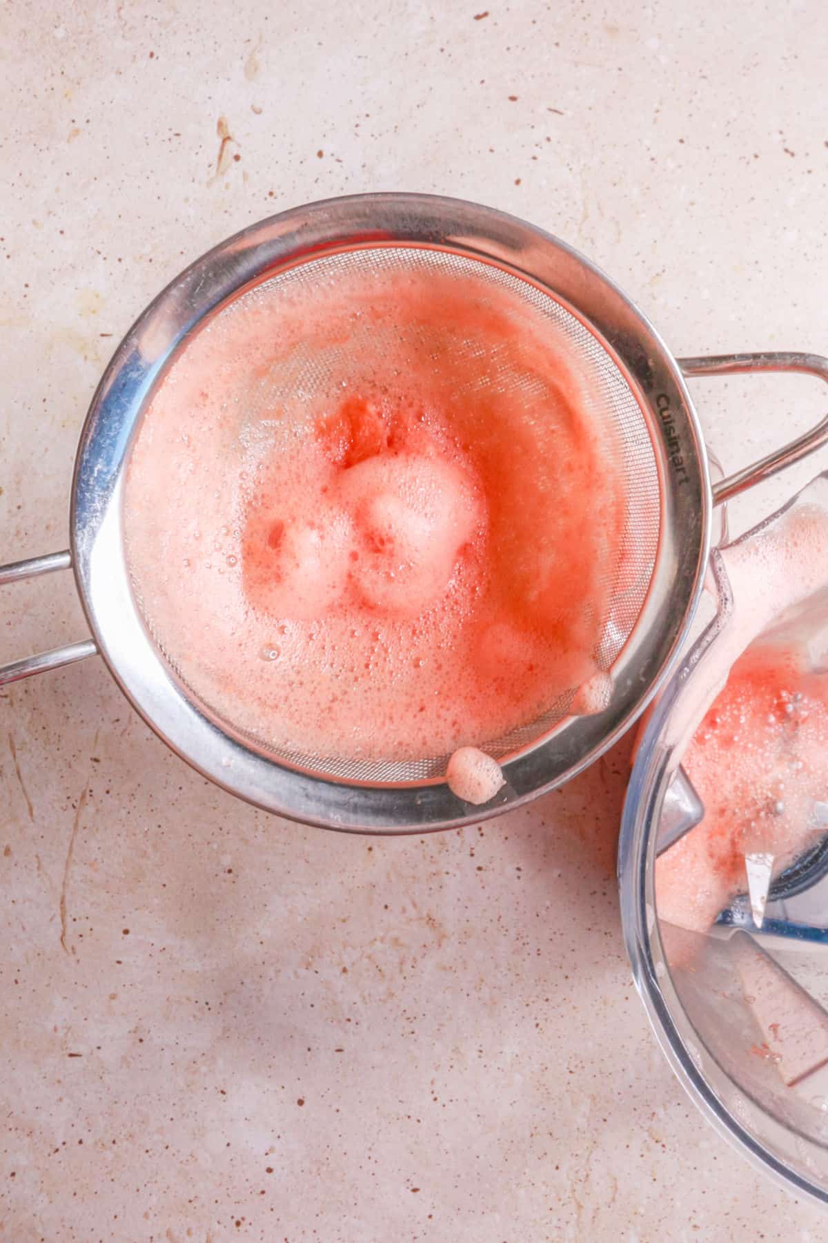 Straining agua fresca through a fine mesh sieve