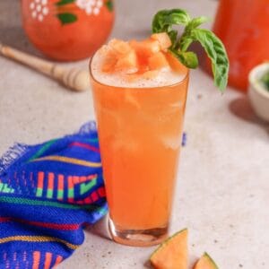 Close up of a glass of cantaloupe basil Agua Fresca garnished with basil