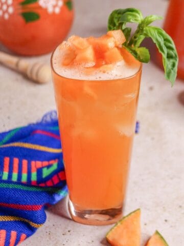 Close up of a glass of cantaloupe basil Agua Fresca garnished with basil