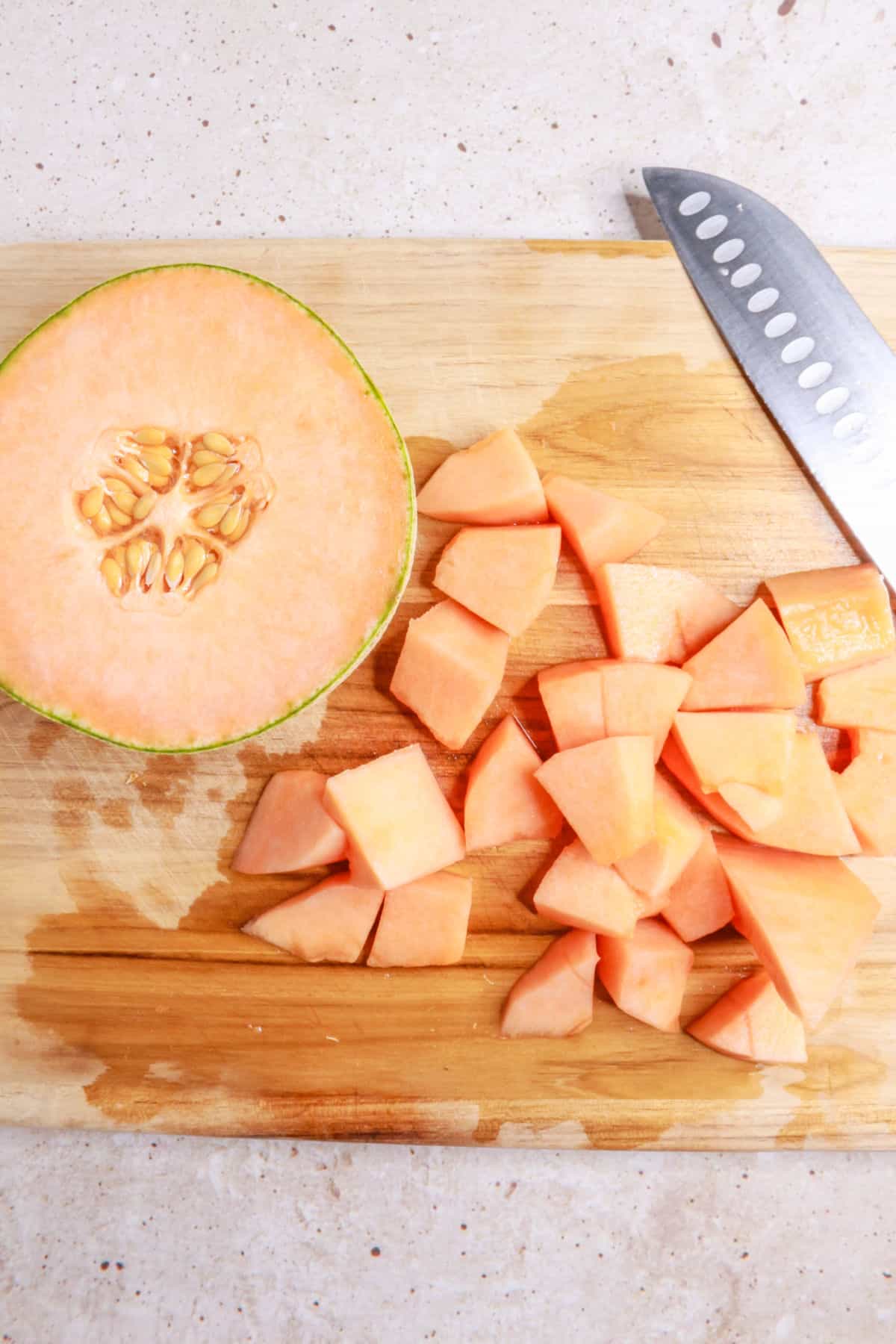 Chopped cantaloupe on a wood cutting board