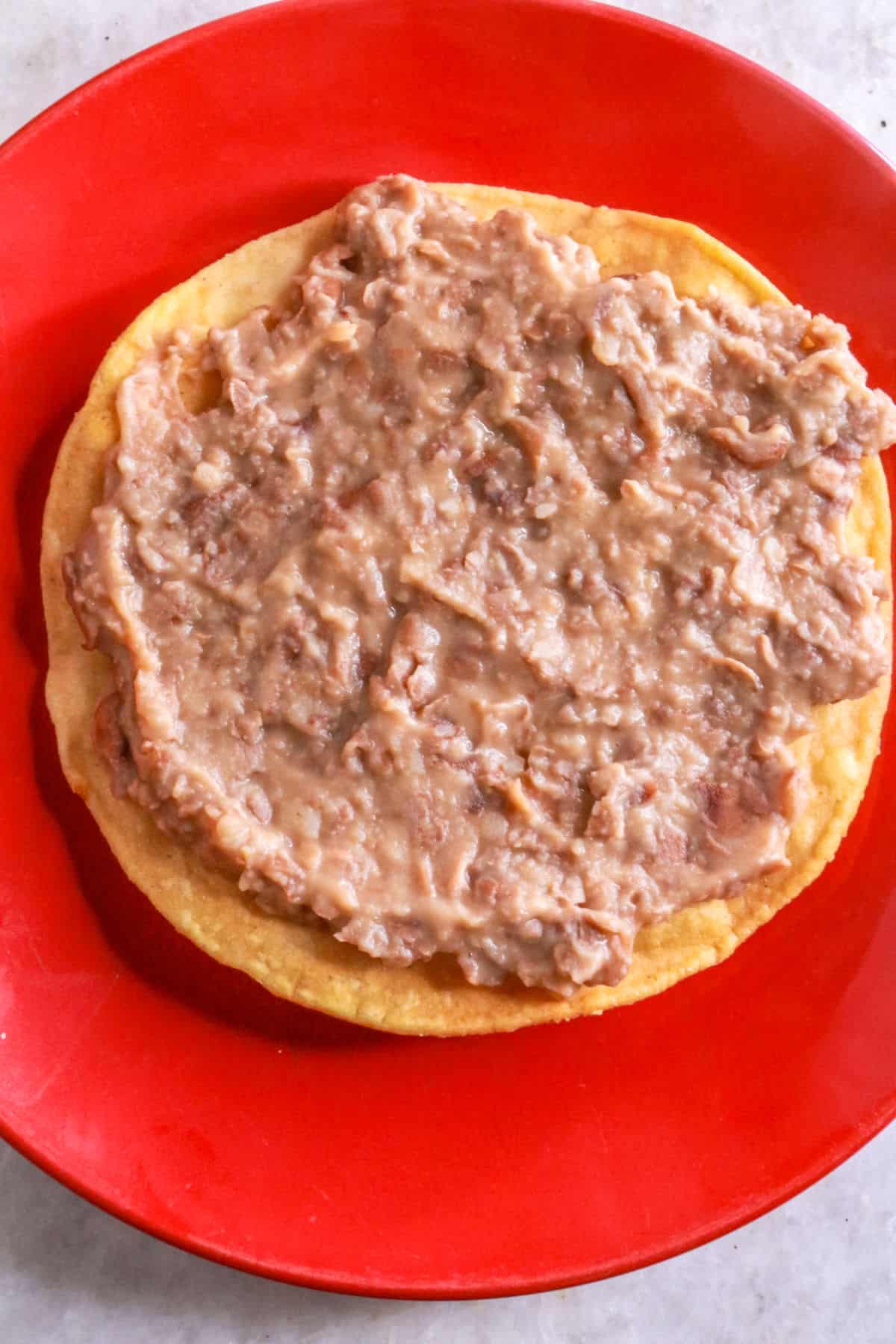 Tostada shell with refried beans spread on top of it